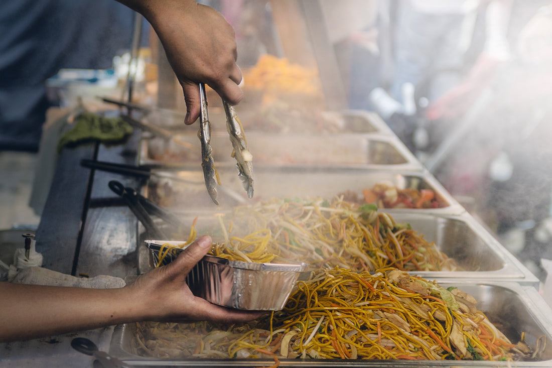 Man serving noodles at a street food market