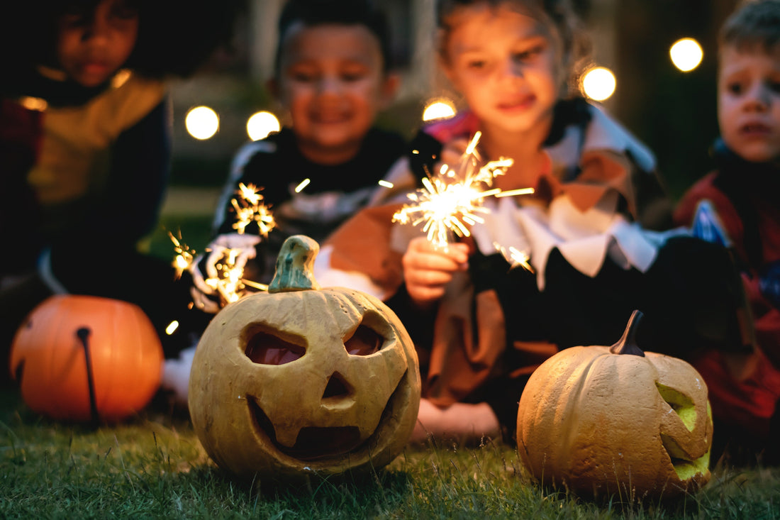 Children holding sparklers, with carved pumpkins for Halloween