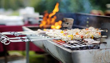 barbecue grill with kebab skewers and meat cooking on flames