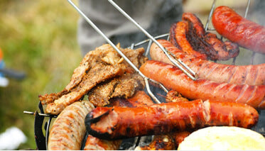 tongs and a bbq hotdog sausage on a commercial bbq grill