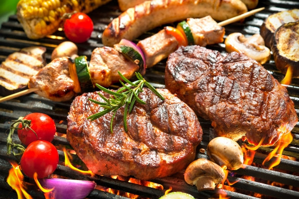 barbecue with vegetables and, burgers, meat, sausages and herbs on a commercial grill