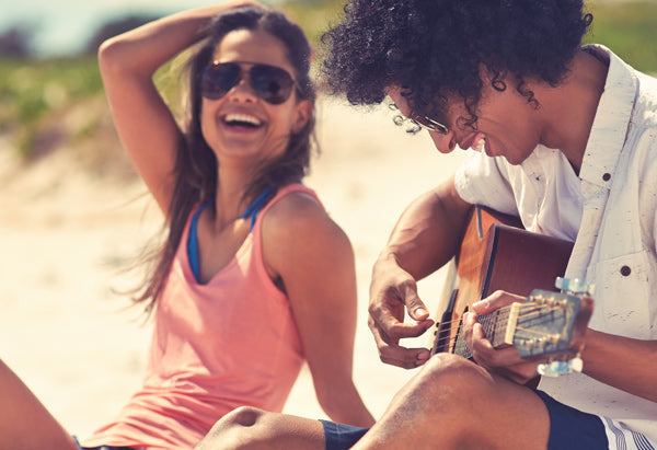 couple on a beach with a guitar having a great time