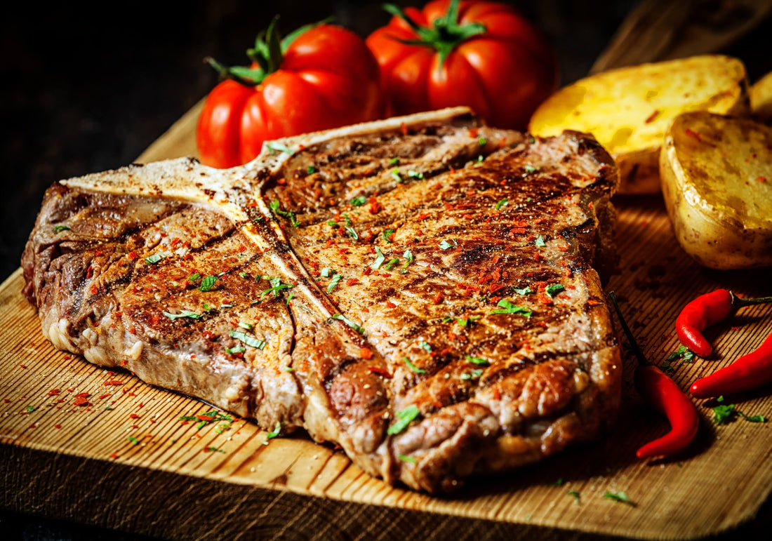t bone steak on a wooden board with chilis, fresh off a commercial barbecue